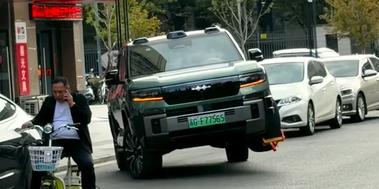 BYD FCB Bao 8 drives on three wheels with wheel clamp attached on public street