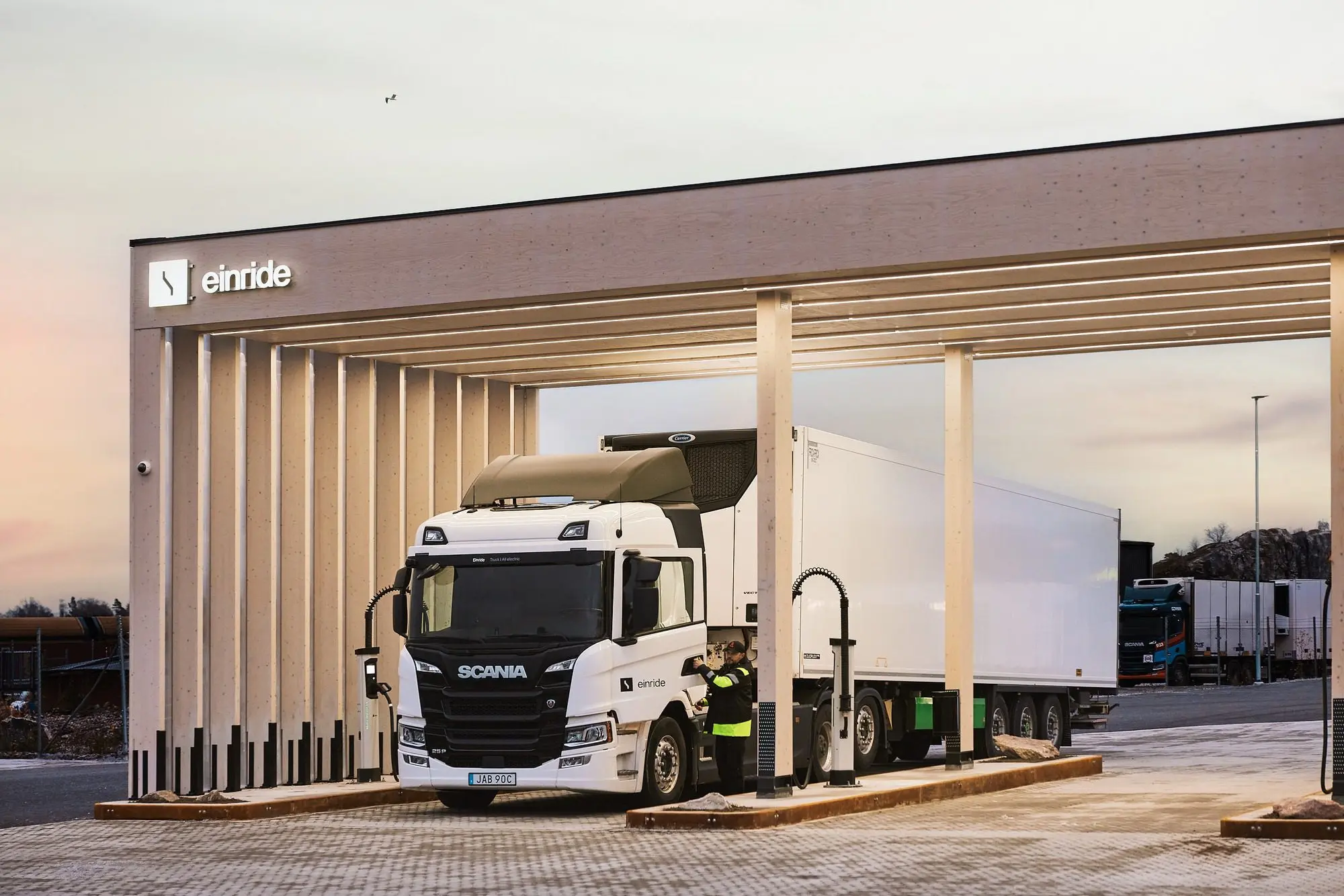 An Einride Scania electric truck charging beneath a timber canopy.