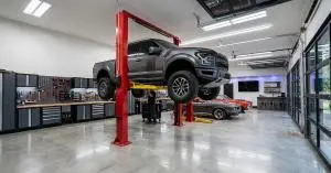 Pickup truck on a red two-post car lift in a home garage