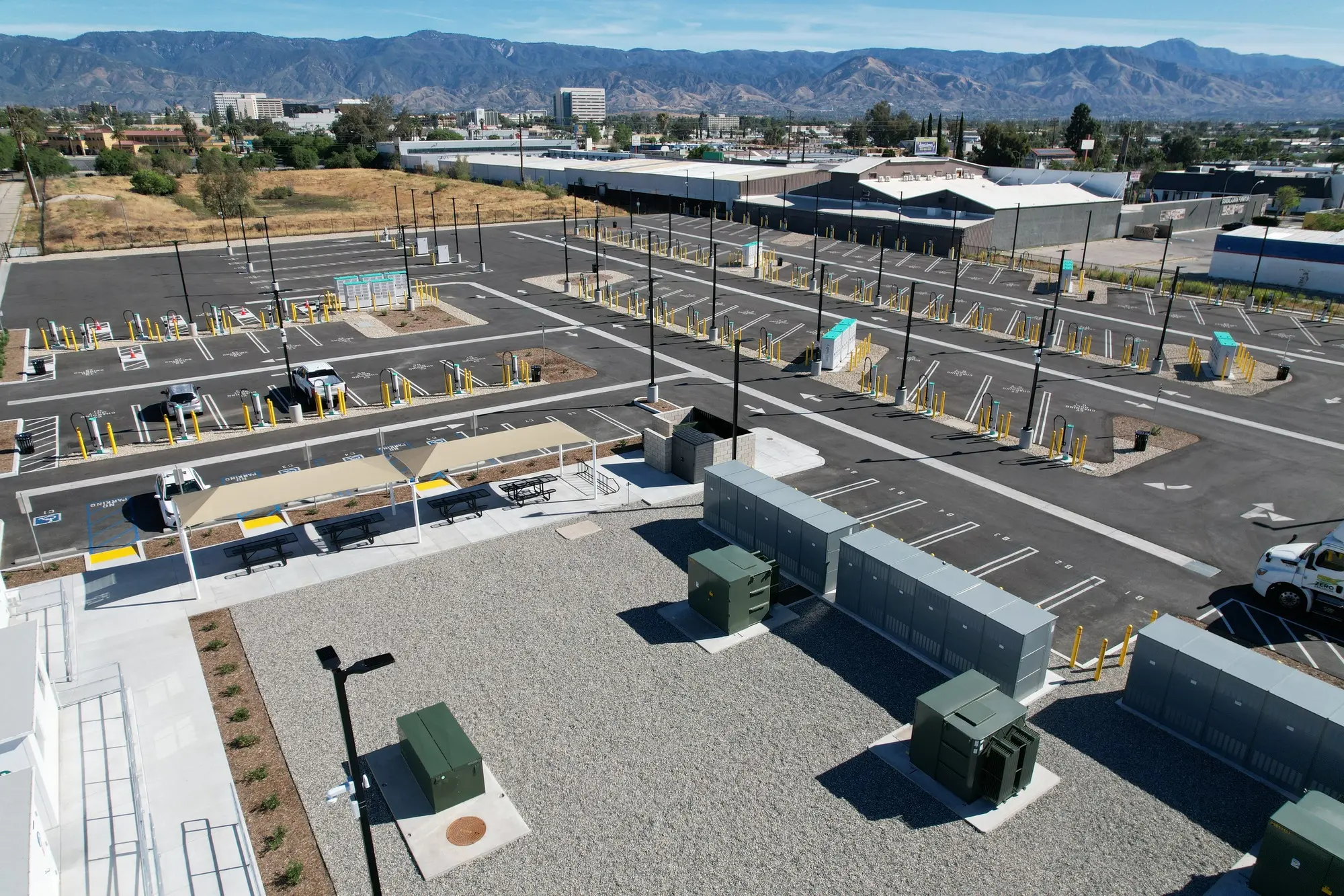 EV Realty’s truck charging bays, shaded seating and electrical equipment, with mountains in the background.