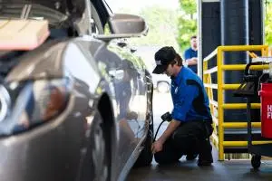 Strickland Brothers technician checks tire pressure on a gray vehicle inside a service bay while performing a ten minute oil change..