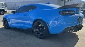 Blue Chevrolet Camaro with black wheels and side splitters, photographed from the rear left.